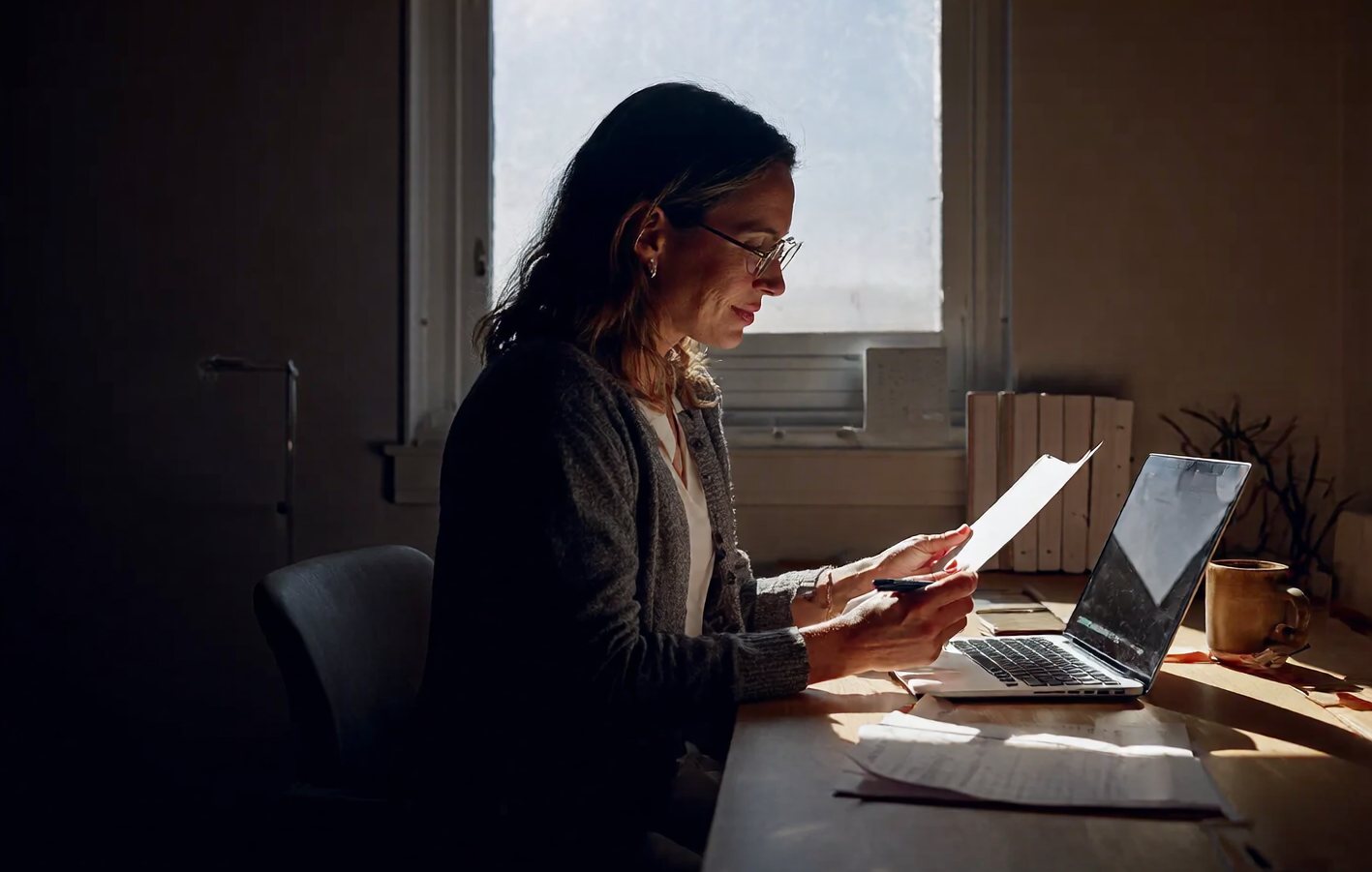A practice owner at her desk reading a drafted reply on her laptop